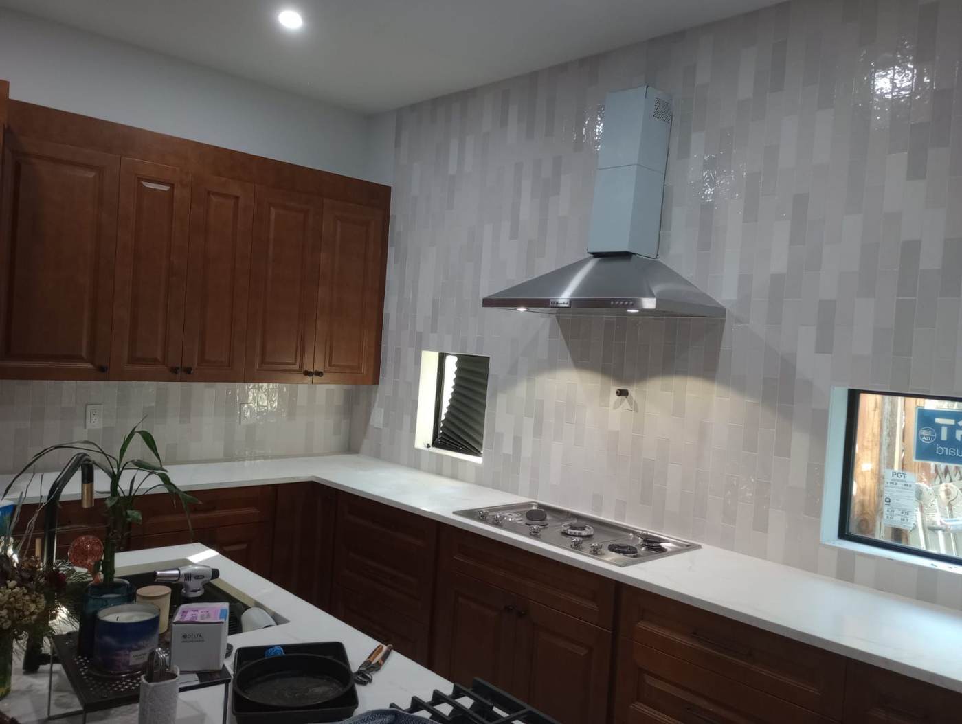 Glazed vertical subway tile backsplash running from the counter up past the range hood