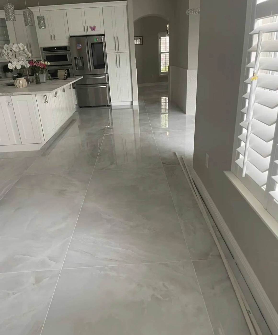 Large-format polished tile floor running through a kitchen and hallway